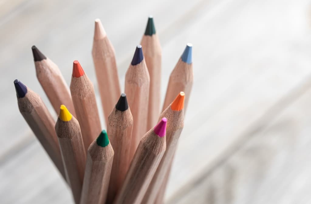 A bouquet of sharpened color pencils with tips facing upward on a light background