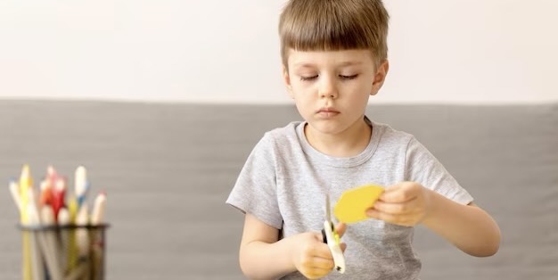 A boy cuts something with scissors