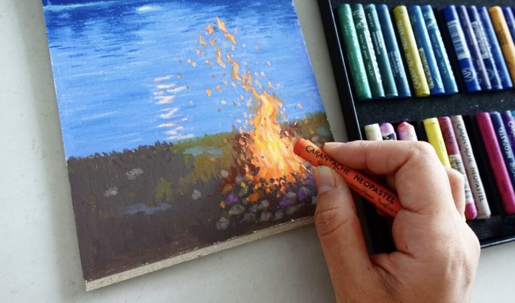 Hand draws a picture with oil pastel