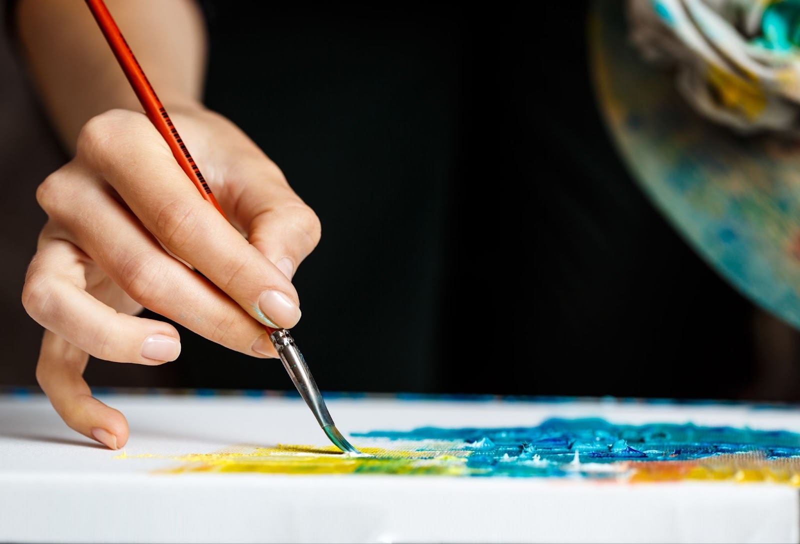 Close up of woman drawing with oil paints on canvas