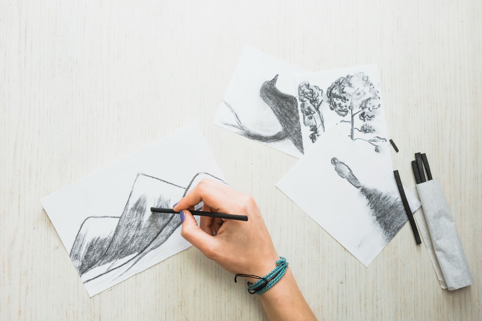 Human's hand sketching on paper with charcoal stick