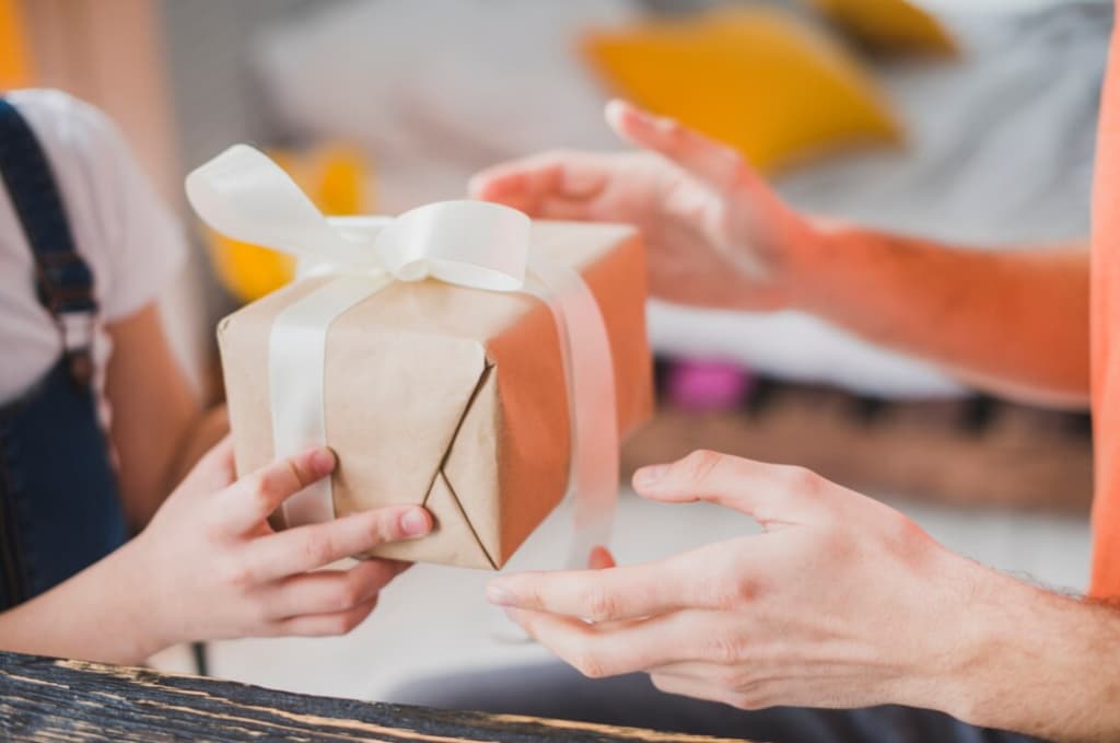 Two people holding and gifting a brown paper-wrapped box with a white ribbon